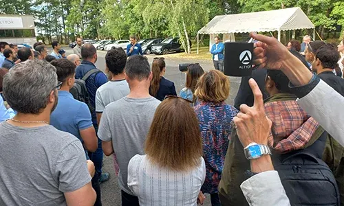 Group of employees gathered outdoors in the Altyor car park, listening to a presentation