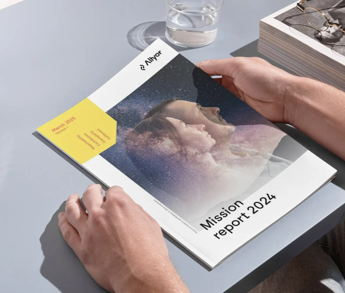 Hands holding the printed Altyor Mission report 2024 on a table