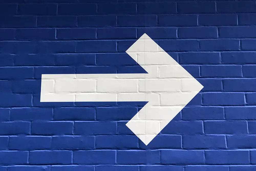 White arrow painted on a blue brick wall