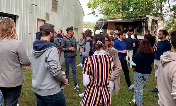 Employees gathered on the grass in front of a food truck, next to an Altyor building