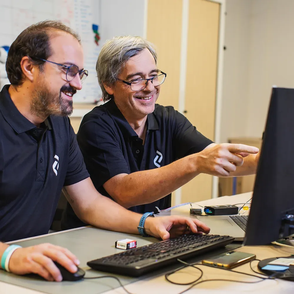 Two smiling Altyor employees working together in front of a computer screen